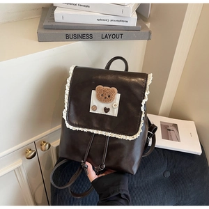 Detailed close-up of dark brown mini backpack with lace trim and cute bear patch decoration