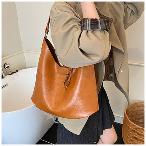 Detailed close-up of caramel brown hobo bag with pebbled leather texture and beaded tassels