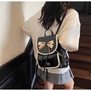 Detail of black glossy backpack with lace trim and bowknot on a model