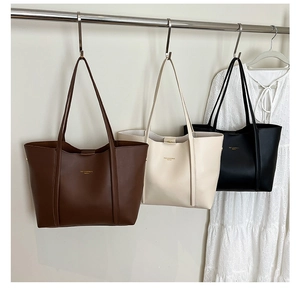 Tre borse tote in pelle marrone beige e nera appese a una rastrelliera in un armadio
