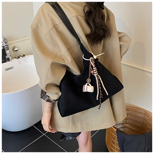 Détail du sac Hobo noir mat avec breloque tasse à café et pompon en cuir tressé