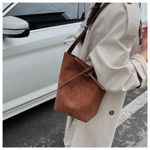 Detail of caramel suede bucket bag showing vintage leather knot and soft texture