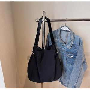 Detail of black nylon tote bag with silver buckle on metal hanger with denim jacket