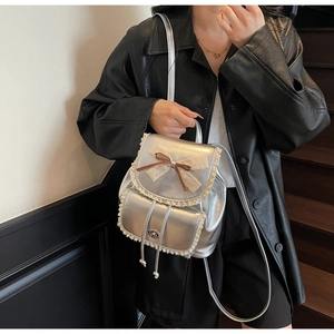 Close-up of silver mini backpack with lace trim and bow knot on a model in leather coat