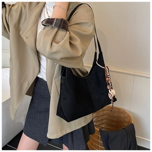 Détail du sac cabas noir avec glands bohèmes et perles en bois pour un look de bureau