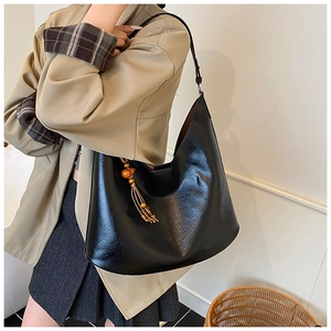 Detail shot of black hobo bag with wood bead tassel and shiny leather texture