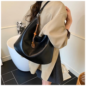 Detail of black pebbled leather bucket bag with wooden bead tassel and metal chain strap