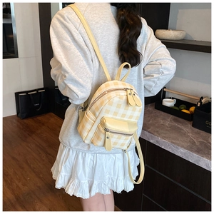 Dettaglio del mini zaino a quadri giallo e beige con spallacci in pelle sulla schiena