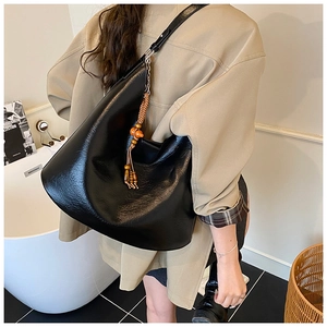 Detail view of large black faux leather hobo bucket bag with wooden bead tassel charm
