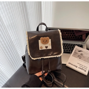 Detailed view of the dark brown PU leather backpack featuring lace edges and plush bear decal