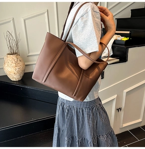 Dettaglio della borsa tote in pelle marrone scuro minimalista con eleganti manici lunghi