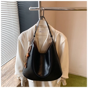 Detail of black pebbled leather hobo bag with minimalist wood bead tassel charm