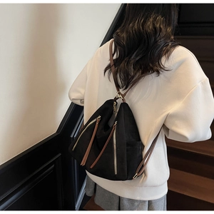 Detail of vintage black suede backpack showing triangle cut design and brown leather zipper pull