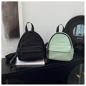 Detail view of mini nylon backpacks in black and mint green on a modern side cabinet