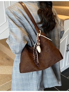 Sac cabas en daim marron mat avec bandoulière en cuir et breloque cœur porté par mannequin