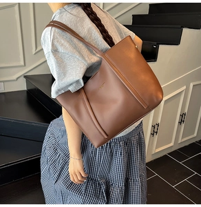 Vista laterale di una grande borsa tote in pelle marrone indossata a spalla