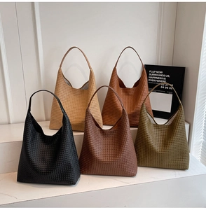 Five woven tote bags in black, yellow, caramel, coffee, and green on white stairs