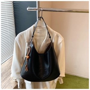 Detail of a black textured hobo bag featuring a wooden bead tassel on a metal hanger