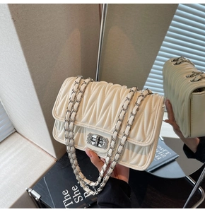Detailansicht der cremefarbenen Stepptasche mit Kristalldrehverschluss und silberner Kette