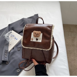 Detail of vintage brown PU backpack with cute lace trim and teddy bear patch ornament