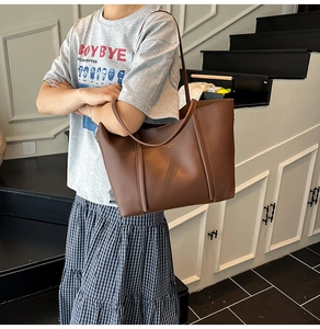 Dettaglio di una grande borsa tote in pelle PU marrone con logo sottile goffrato in oro