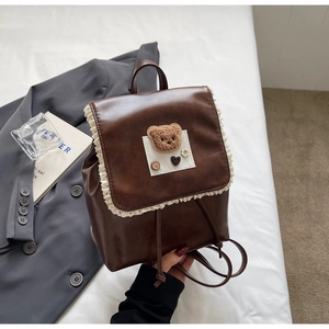 Detailed view of dark brown faux leather mini backpack with lace trim and plush bear