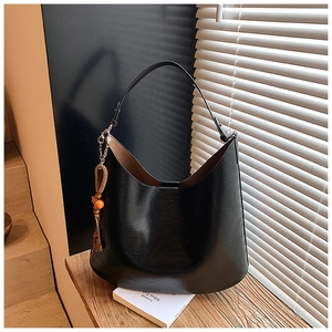Close-up of black PU leather hobo bag with vintage oil-wax finish and wood bead tassel
