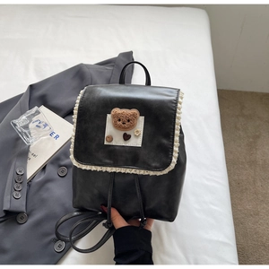 Close-up of black PU leather backpack with white lace trim and plush bear detail