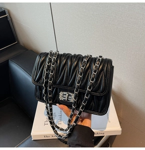 Detail einer schwarzen gesteppten Ledertasche mit kristallbesetztem Drehverschluss