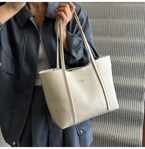 Dettaglio della borsa tote in pelle crema con elegante logo dorato e trama a grana fine