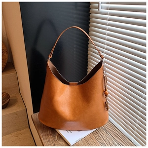 Close-up of caramel hobo shoulder bag with leather texture and tassel bead detail