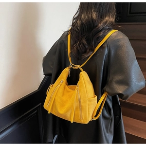 Detail of bright yellow textured faux suede backpack with decorative gold zippers