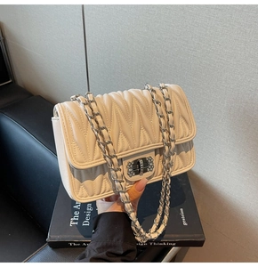 Detailaufnahme der beigen Stepptasche mit silbernem Drehverschluss und Strasssteinen