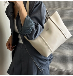 Dettaglio di una borsa tote minimalista color crema con stampa di lettere su modella