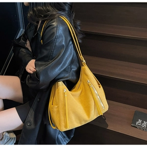Detail of yellow hobo shoulder bag with metal zippers and long tassel decorations