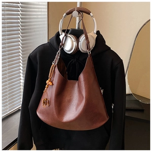 Detail of dark brown Hobo bag featuring wood bead tassel and smooth leather texture