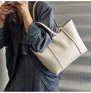 Dettaglio della borsa tote in pelle bianco crema con logo dorato e struttura a coste