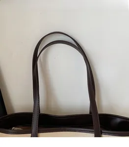 Detail of canvas tote bag with brown leather shoulder straps and reinforced stitching