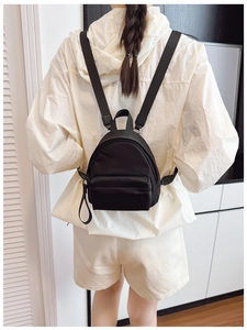 Mini black nylon backpack on model showing portable travel size and water-resistant texture