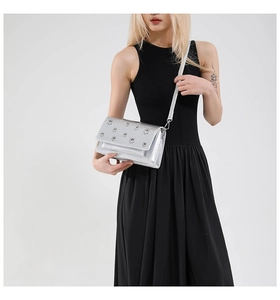 Detail view of silver baguette bag with metal eyelets and adjustable leather shoulder strap