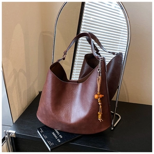 Detail of a vintage dark reddish-brown hobo shoulder bag with a woven tassel charm
