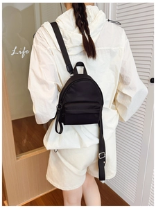 Detailed back view of a black nylon mini backpack worn by model showing compact size