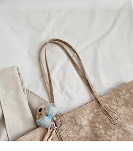 Makroaufnahme einer Jacquard-Canvas-Tasche mit Blumenmuster, Schultergurten und Bär