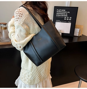 Dettaglio della borsa tote in pelle nera con logo dorato e cuciture eleganti