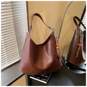 Detail of vintage brown Hobo bag with stylish wooden beads tassel and silver chain strap