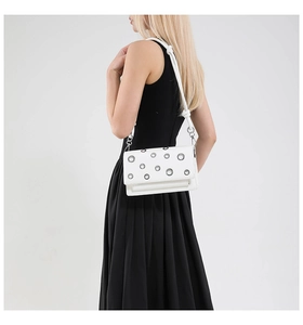 Detail of white leather shoulder bag with silver metal eyelets and knotted strap design
