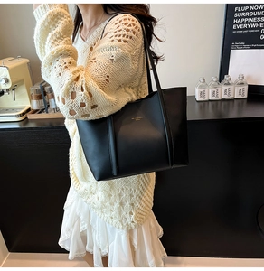 Elegante borsa tote in pelle nera opaca con logo dorato indossata per il look quotidiano