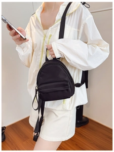 Detailed view of lightweight black mini nylon backpack with adjustable fabric straps