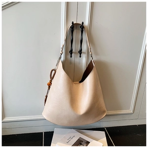 Detailed close-up of beige hobo bag textured leather surface and wooden bead charm