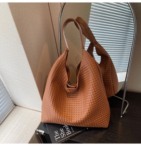 Detail of a deep brown woven tote bag showing leather texture and intricate hobo style pattern